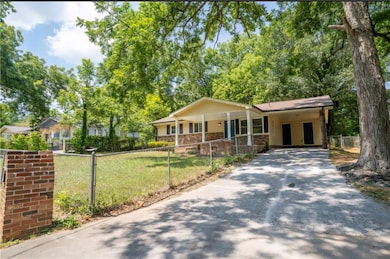 Single story home with concrete driveway, a fenced front yard, a carport, and a porch