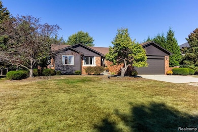 Single story home with a front yard, concrete driveway, brick siding, and an attached garage