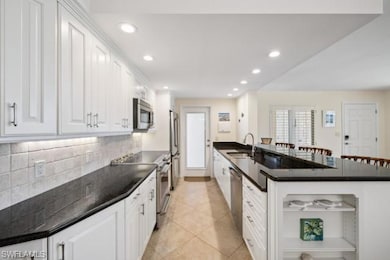 Kitchen featuring appliances with stainless steel finishes, open shelves, white cabinets, backsplash, and recessed lighting