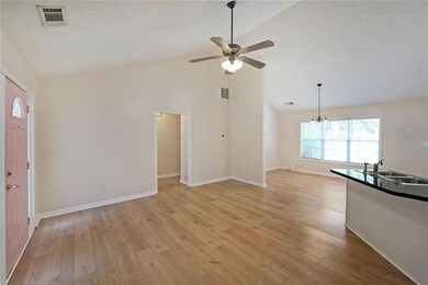 Unfurnished living room featuring ceiling fan, a chandelier, light wood-type flooring, and high vaulted ceiling