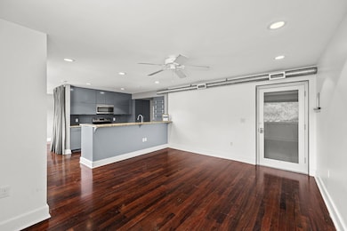 Unfurnished living room with ceiling fan, dark wo