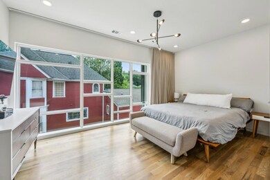Upstairs, the Spacious Primary Suite feels like a High-End Hotel Escape, featuring a Wall of Windows, Large Walk-In Closet, and a Spa-Inspired Bathroom with Stone Double Vanity, Glass-Enclosed Shower, and Designer Finishes.