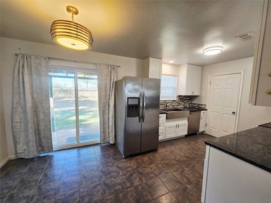 Kitchen featuring new white cabinets, stainless steel appliances, decorative backsplash, and dark tile patterned flooring