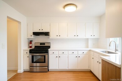 Kitchen with gas stove, tasteful backsplash, light wood-type flooring, and white cabinets