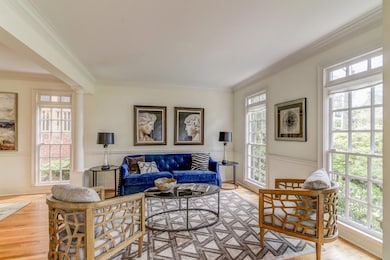 Living area featuring crown molding, plenty of natural light, ornate columns, and light wood-style flooring