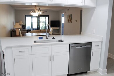 Kitchen with white cabinetry, stainless steel dishwasher, light stone counters, open floor plan, and ceiling fan