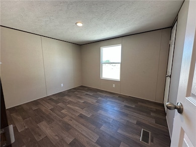 Unfurnished room with dark wood finished floors and a textured ceiling