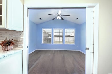 Unfurnished living room featuring dark wood-style flooring, vaulted ceiling, and ceiling fan