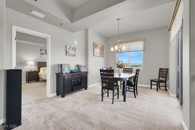 Carpeted dining area with a chandelier and baseboards