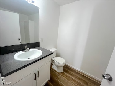 Half bath featuring wood finished floors, vanity,