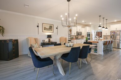 Dining room with a notable chandelier, wood finished floors, and crown molding