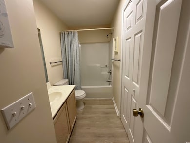 Bathroom with toilet, vanity, wood finished floors, and shower / bath combo