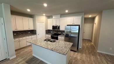 Kitchen with white cabinetry, appliances with stainless steel finishes, a kitchen island with sink, and sink