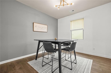 Dining room featuring dark wood-style flooring and a chandelier