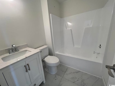 Bathroom with washtub / shower combination, vanity, and light marble finish floors