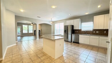 Kitchen featuring decorative backsplash, light stone counters, arched walkways, open floor plan, and white cabinets