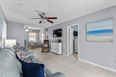 Living room with light wood-style floors, ceiling fan, a textured ceiling, and baseboards