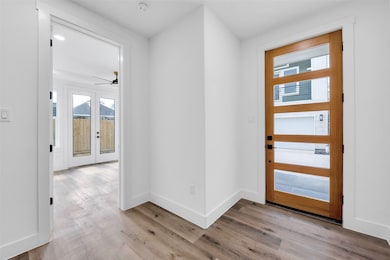 The modern door and entryway leads to a spacious foyer. The door to the left leads to one of three bedrooms with an ensuite bath.