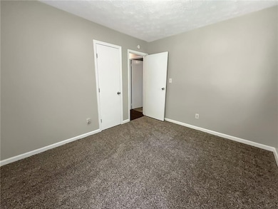 Unfurnished bedroom featuring dark carpet, a textu