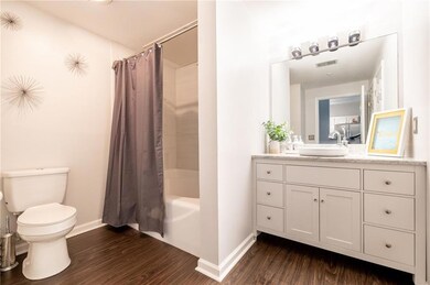 Full bathroom featuring baseboards, wood finished floors, toilet, vanity, and shower / tub combo with curtain