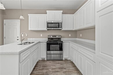 Kitchen with appliances with stainless steel finishes, sink, kitchen peninsula, and pendant lighting
