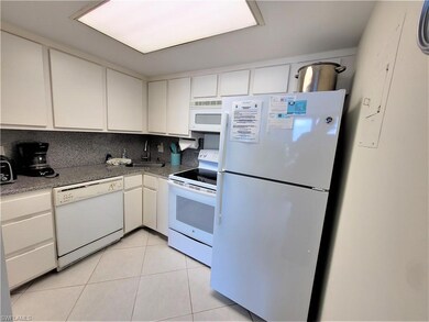 Kitchen with white appliances, white cabinets, backsplash, and light tile patterned flooring
