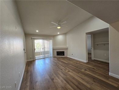 Unfurnished living room featuring dark wood finished floors, a ceiling fan, a fireplace, recessed lighting, and a textured wall