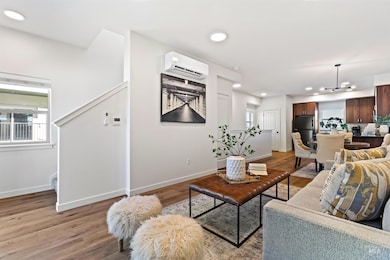 Living room featuring light wood-style flooring, an AC wall unit, recessed lighting, and a chandelier