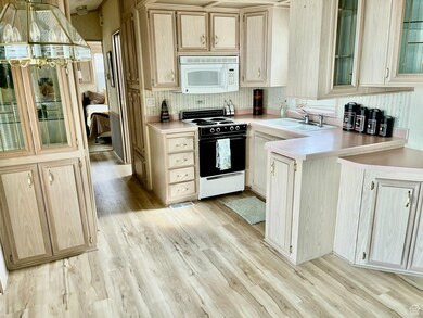 Kitchen featuring glass insert cabinets, range with electric cooktop, white microwave, light countertops, and a peninsula