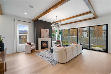Living area featuring beamed ceiling, a large fireplace, light wood finished floors, a chandelier, and recessed lighting