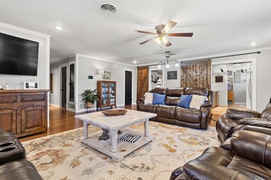 Living room with crown molding, a ceiling fan, ba
