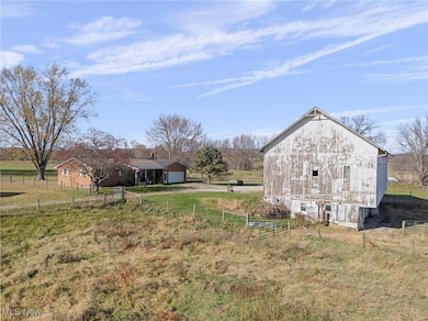View of yard with an outdoor structure, a view of rural / pastoral area, a garage, a barn, and driveway