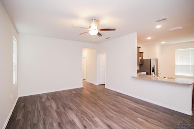 Unfurnished living room featuring dark wood-type flooring, a ceiling fan, baseboards, recessed lighting, and plenty of natural light