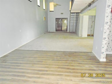 Empty room featuring a towering ceiling and wood finished floors