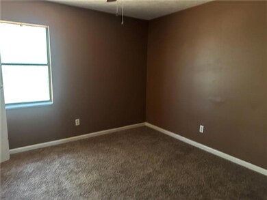 Empty room with baseboards and dark colored carpet