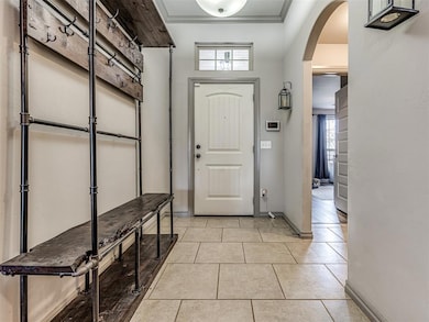 Entryway with crown molding and light tile floors