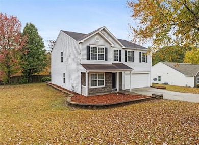 Traditional-style house with concrete driveway, a porch, a garage, and stone siding