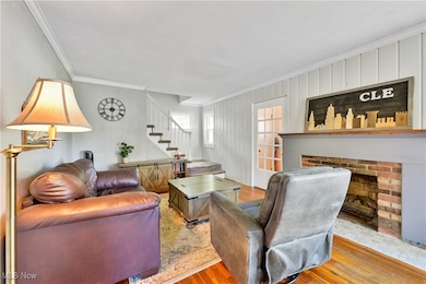 Living room with ornamental molding, wood finished floors, a fireplace, and stairs