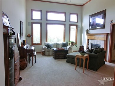 A great room with a wall of windows & a fireplace.