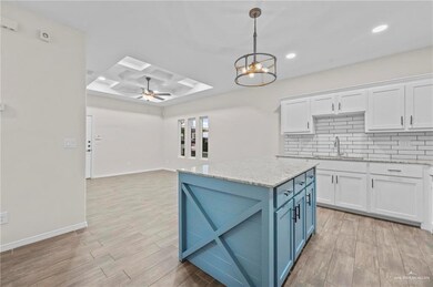 Kitchen featuring hanging light fixtures, sink, light hardwood / wood-style flooring, and white cabinets