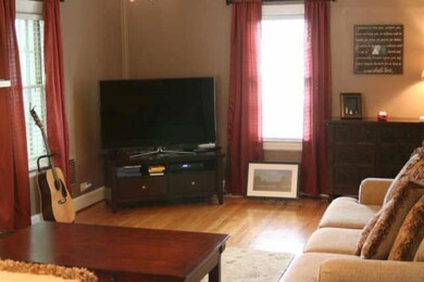 large livingroom with fireplace, ornate crown mouldings and hardwood floors.