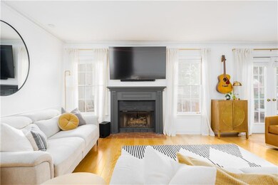 Living area featuring wood finished floors, a fireplace with flush hearth, and crown molding