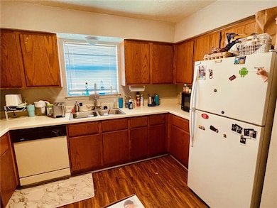 Kitchen featuring a sink, white appliances, dark w