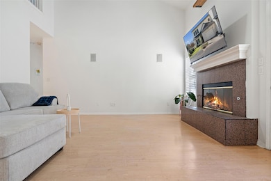 Living area featuring a high ceiling, light wood finished floors, and a fireplace