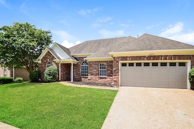 View of front of property featuring brick siding, a front lawn, driveway, and an attached garage