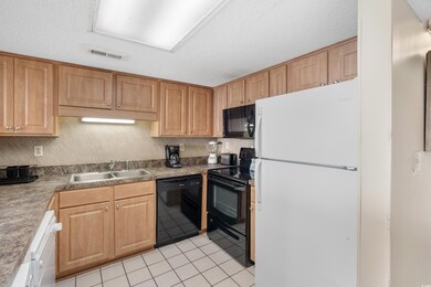 Kitchen featuring visible vents, black appliances, a sink, a textured ceiling, and light tile patterned floors