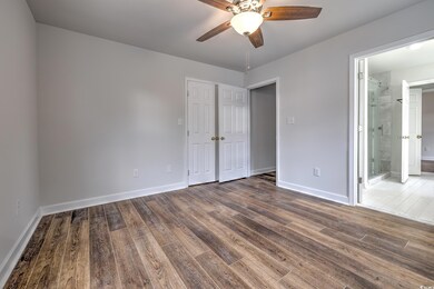 Unfurnished bedroom with connected bathroom, ceiling fan, and hardwood / wood-style flooring