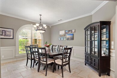 Dining area with crown molding, a textured ceiling, light tile flooring, and an inviting chandelier