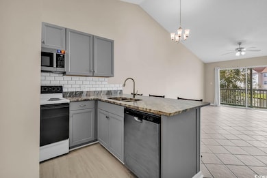 Kitchen featuring gray cabinets, stainless steel appliances, tasteful backsplash, a peninsula, and pendant lighting
