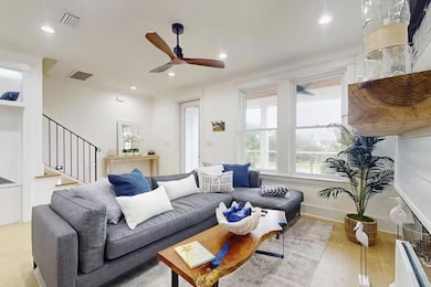 Living area with a ceiling fan, recessed lighting, wood finished floors, and stairs